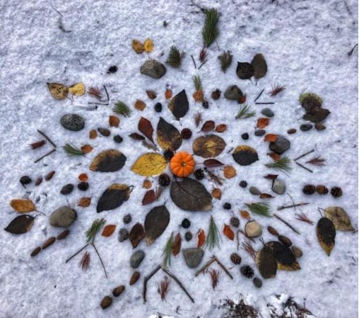 Leaves, sticks and rocks on snow in a snowflake design