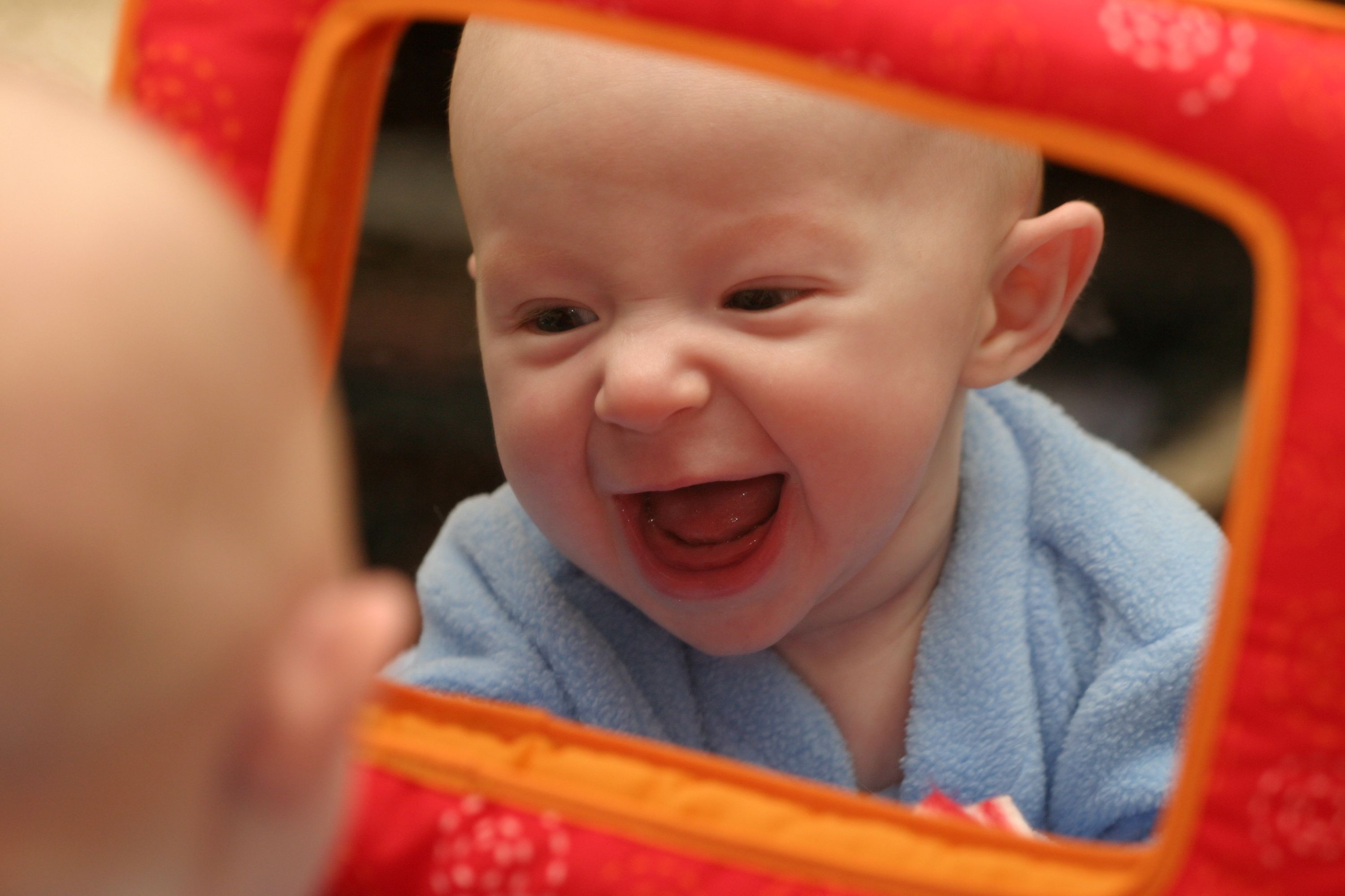 Infant smiling face looking at self in mirror 