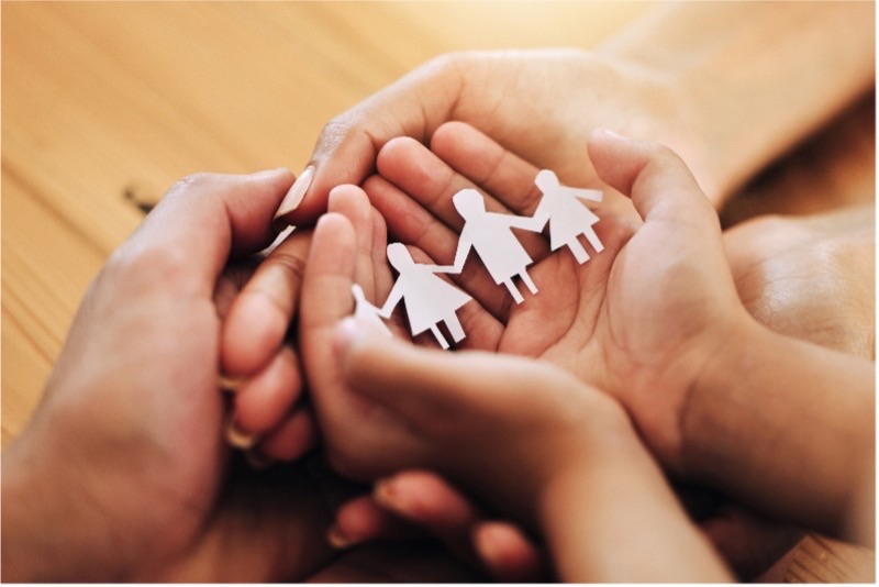 Adult hands holding child hands holding paper chain family