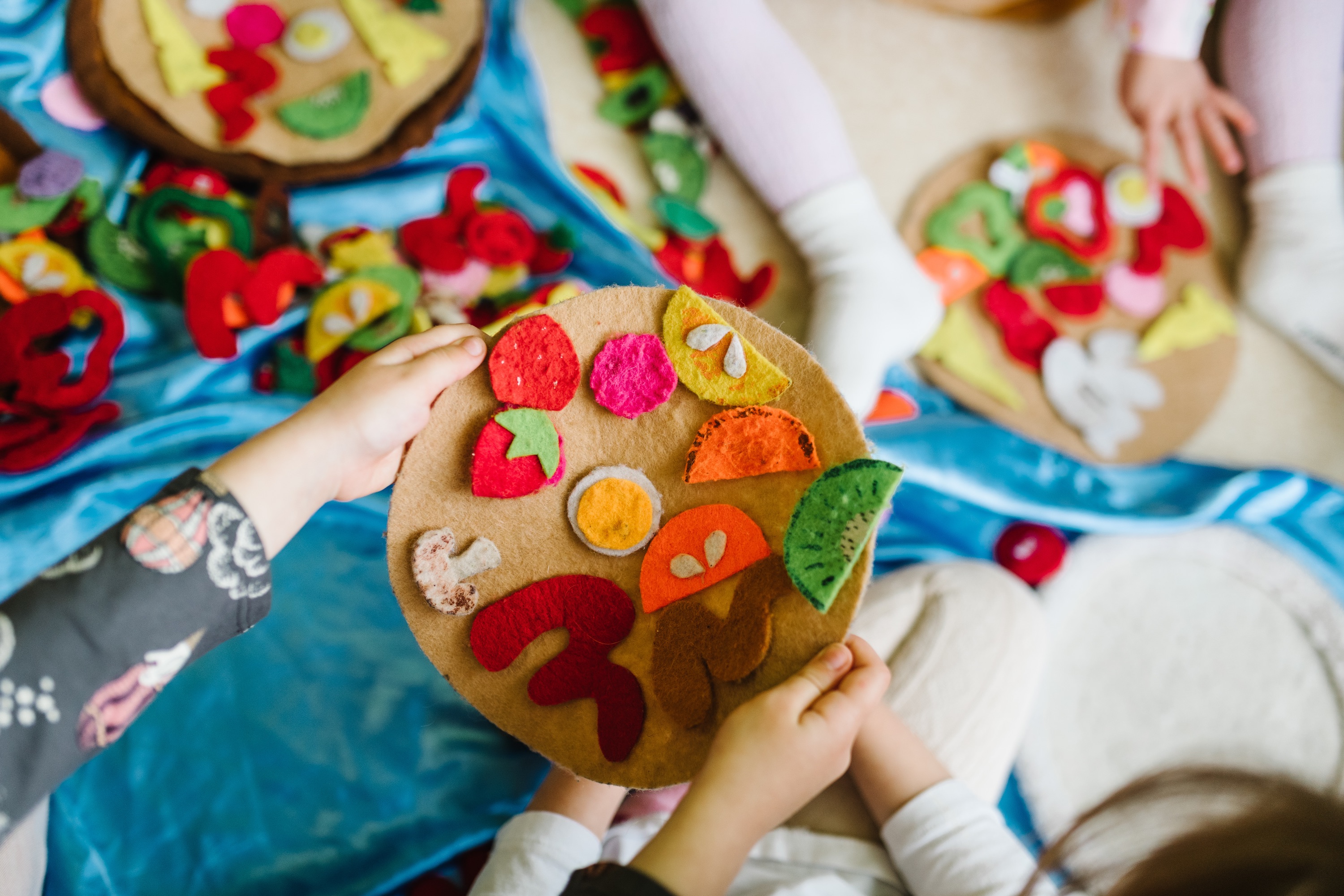 Des enfants jouent avec des aliments-jouets en feutre.