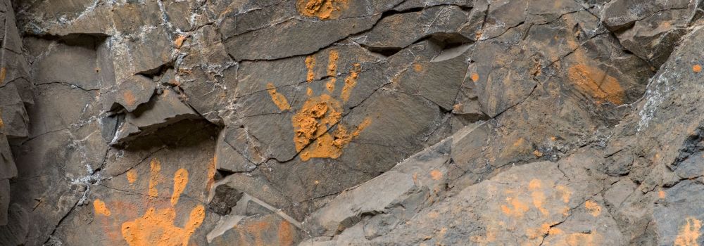 Orange handprints on rock
