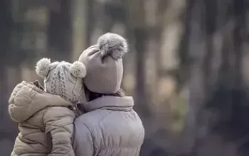 Adult holding child outside in winter