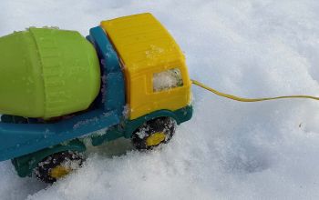 Brightly coloured toy cement mixer in the snow.